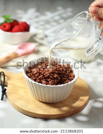 POur Milk to the Bowl with Chocolate Flavoured Rice Crispy, Breakfast Cereal in a White Bowl 