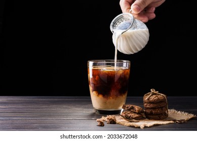 Pour milk into coffee cup on black background
