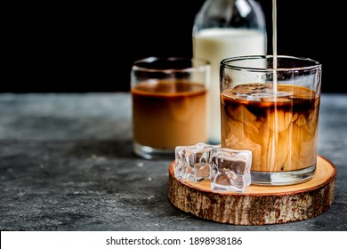 Pour the milk into a glass with cold brewed coffee on a black background - Powered by Shutterstock