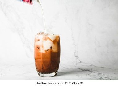 pour milk and make Iced cocoa in clear glass on marble, copy space for your text - Shutterstock ID 2174912579