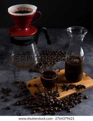 Pour over coffee brewing process with red dripper and glass server on dark moody background.