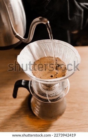 Pour over filter with ground coffee in the funnel in focus. Drip filter coffee brewing. Pour over alternative method of pouring water over roasted and ground coffee beans contained in filter