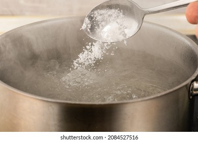 Pour Salt Into A Metal Pot With Boiling Water With A Spoon