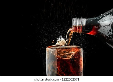 Pour Soft Drink In Glass With Ice Splash On Dark Background.