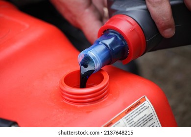 Pouring 2 Т Oil Into Gasoline. Preparation Of A Fuel Mixture For A Two Stroke Outboard Motor.