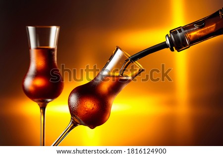 Pouring alcoholic drink in glass with natural ice. Steamed glasses with strong alcoholic drink. Copy space.