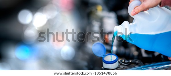 Pouring antifreeze. Filling\
a windshield washer tank with an antifreeze in winter cold weather.\
panorama