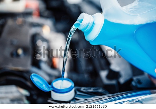 Pouring antifreeze. Filling a\
windshield washer tank with an antifreeze in winter cold\
weather.
