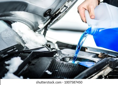 Pouring antifreeze liquid for washing car screen. 