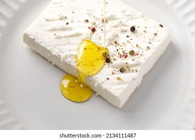 Pouring aromatic olive oil on delicious feta cheese with pepper and spices. Clean. White plate - Powered by Shutterstock