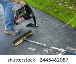 Pouring asphalt sealant on driveway to repair cracks