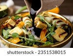 Pouring balsamic vinegar onto delicious salad with tofu and vegetables in bowl, closeup