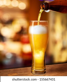 Pouring Beer In Glass On Bar Or Pub Desk