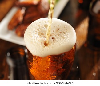 pouring beer into glass with bbq chicken wings in background 01