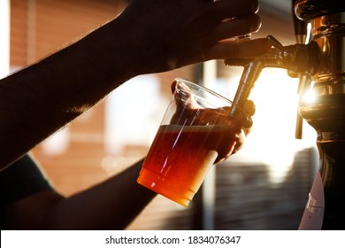 Pouring beer into a plastic glass. Sunset - Powered by Shutterstock