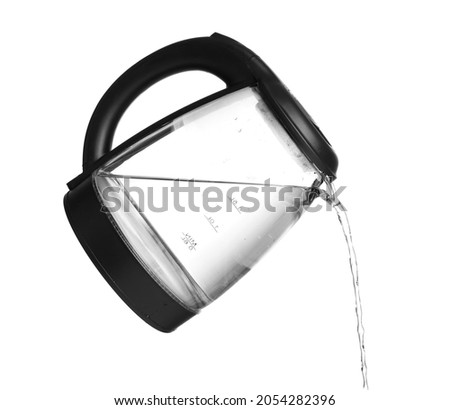 Pouring of boiled water from electric kettle on white background