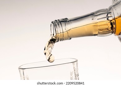 Pouring Bourbon Whiskey Into A Glass From The Neck Of A Bottle Close-up White Background Gradient