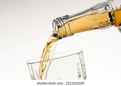 Pouring Bourbon Whiskey Into A Glass From The Neck Of A Bottle Close-up White Background