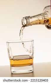 Pouring Bourbon Whiskey Into A Glass Close-up White Background Vertical Photo