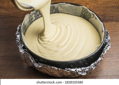 Pouring Cake Mixture Into A Cake Tin Line With Paper And Wrap With Aluminum Foil For Baking Cheesecake.