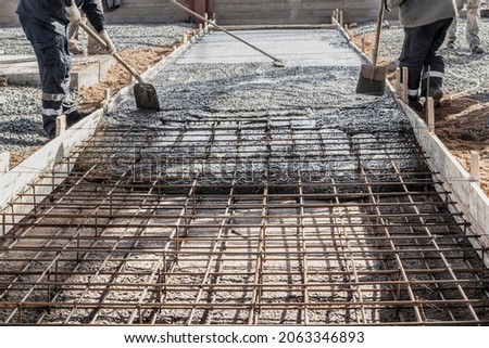Pouring cement or concrete with a concrete mixer truck, construction site with a reinforced grillage foundation, start of construction of a production workshop