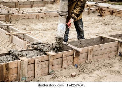 Pouring cement into a wooden formwork for the Foundation of a building that is being built. - Shutterstock ID 1742594045