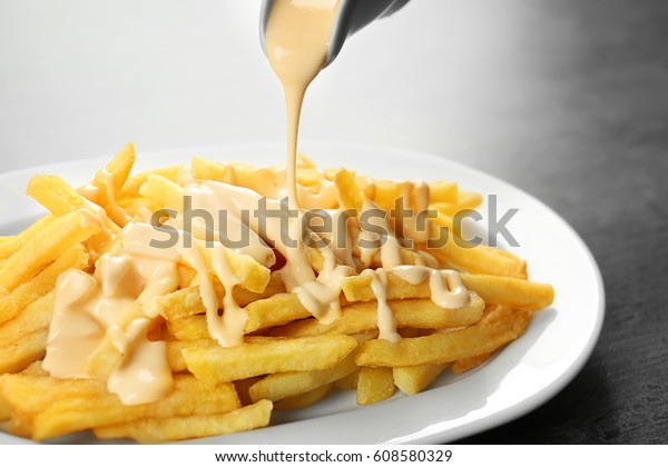 Pouring cheese\
sauce on french fries,\
closeup