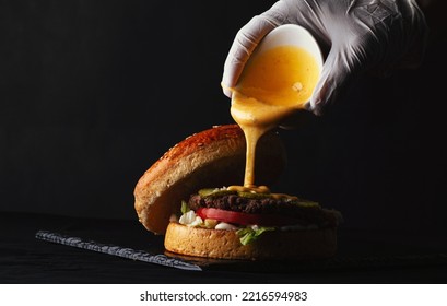 Pouring Cheese Sauce On A Lamb Burger  Black Back Ground 