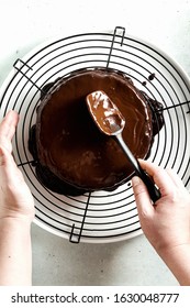 Pouring Chocolate Ganache On The Cake. Female Hands