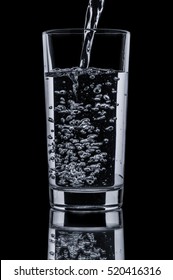 Pouring Clear Water In Glass On Black Background