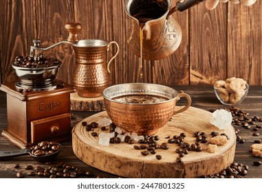 Verser du café de la cafetière dans une tasse en cuivre, un broyeur à café ancien et une jug de lait en cuivre sur fond bois. : photo de stock