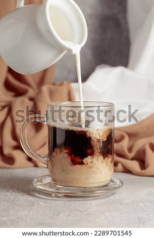 Similar – Image, Stock Photo Pouring coffee from a french press into a white cup, in front of a glass background and a stripped placemat