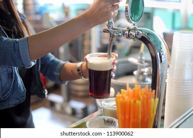 Pouring dark beer to plastic glass from beer tap - Powered by Shutterstock