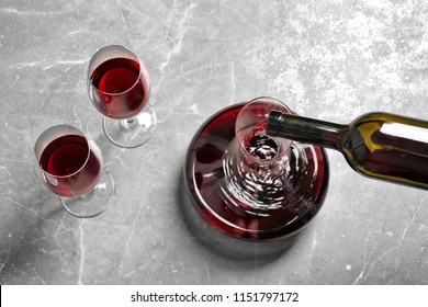Pouring delicious red wine into decanter on grey table, above view