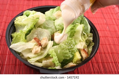 Pouring Dressing Over Lettuce For A Caesar Salad