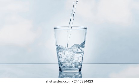 pouring drinking water in a transparent glass isolated on abstract background with glass table, water resource concept with copy space