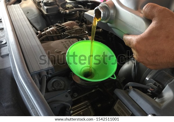 Pouring engine oil to car engine. Fresh oil poured\
during an oil change to a\
car.