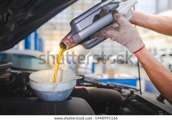 Pouring engine oil into the engine room., Gold oil\
during car oil change in the repair shop or service\
center.,interior car-care\
center