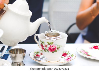 Pouring And Filtering Hot Tea During Afternoon Snack Time.