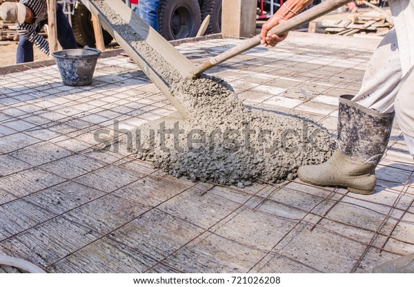Pouring fresh concrete from electrical\
mixer car and construction worker plastering\
cement.