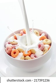 Pouring Fresh Creamy Milk Into A Bowl Of Colorful Fruit Loops Breakfast Cereal In A White Ceramic Bowl With A Splash On A White Background With Copyspace