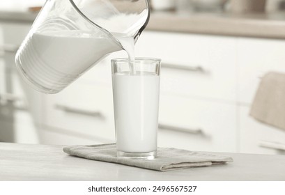 Pouring fresh milk from jug into glass at light wooden table in kitchen, closeup - Powered by Shutterstock