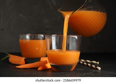 Pouring Freshly Made Carrot Juice Into Glass On Black Table