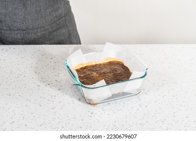 Pouring fudge mixture into the baking pan lined with parchment paper to prepare chocolate peanut butter fudge. - Powered by Shutterstock