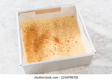 Pouring fudge mixture into the square cheesecake pan lined with parchment paper to prepare eggnog fudge. - Shutterstock ID 2254998705