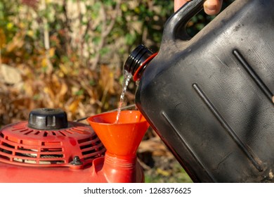 Pouring Gasoline Into The Tank Of  Lawn Mower.