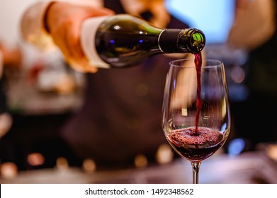 Pouring glass of red wine from a bottle.
