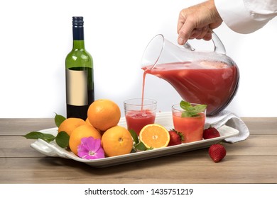 Pouring A Glass Of Sangria Cocktail Drink With A Dark Red Wine Bottle With Generic Label Oranges And Strawberries On The Table