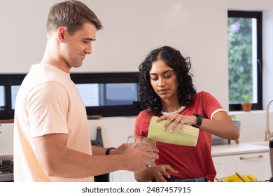 Pouring green smoothie into glasses, young couple enjoying healthy drink in kitchen. lifestyle, nutrition, wellness, fresh, detox, organic - Powered by Shutterstock