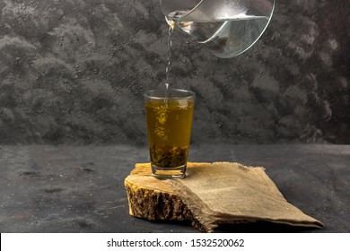 Pouring green tea with boiling water from a transparent glass teapot. Antioxidant and toxin-removing tea into a glass after spa, copy space. 